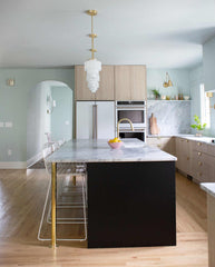 pale wood and pastel blue kitchen renovation with modern cabinetry, brass details, and art deco inspired  pendant lighting