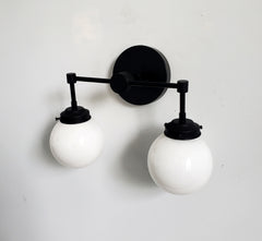 two light matte black wall sconce with white globe shades