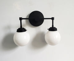 two light matte black wall sconce with white globe shades