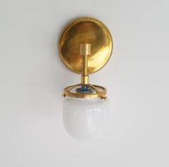single brass bathroom sconce with glass