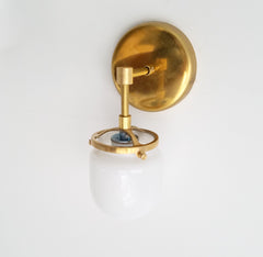 single brass bathroom sconce with glass