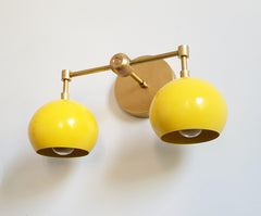 yellow and brass sconce with round eyeball shades for bathrooms