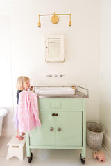 brass sconce over a vintage mint bathroom vanity