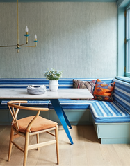 Adele Chandelier in brass with teal blue scalloped accents, installed above a sleek wood dining table with blue-and-white striped built-in banquette seating and pastel teal trim. This chandelier brings sculptural drama, colorful retro-inspired design, and soft ambient glow to breakfast nooks or dining areas. A customizable modern chandelier perfect for eclectic, coastal, or midcentury-inspired interiors.