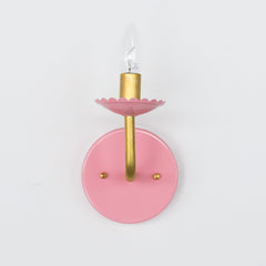 pastel pink and brass wall sconce with scalloped bobesche detail