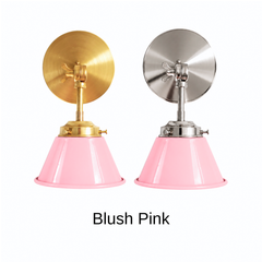 A pale pink wall sconce with a glossy cone shade, shown in Blush Pink with brass or nickel hardware. It has a single light, a round backplate, and a swivel knuckle with a wing nut so you can tilt the shade toward a bed, a mirror, or a sink. Use it as a bedside sconce in a nursery or bedroom, a vanity light in a powder room, or a pair in a kitchen. Soft pink sits well with cream walls, white tile, and warm brass, so it suits pastel, cottage, and grandmillennial rooms.