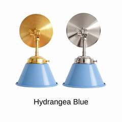 A powder blue wall sconce with a glossy cone shade, shown in Hydrangea Blue with brass or nickel hardware. It has a single light, a round backplate, and a swivel knuckle with a wing nut so you can angle the shade toward a bed, a mirror, or a counter. Use it as a bedside sconce, a vanity light in a bathroom, or a pair by a kitchen window. Powder blue pairs well with chinoiserie, blue and white porcelain, and floral wallpaper, so it suits grandmillennial, French country, and traditional rooms.