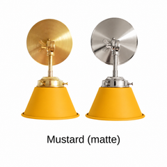 A mustard yellow wall sconce with a matte cone shade, shown in Mustard with brass or nickel hardware. It has a single light, a round backplate, and a swivel knuckle with a wing nut so you can angle the shade toward a bed, a mirror, or a counter. Hang one by a bed for reading, a pair beside a bathroom mirror as a vanity light, or one over a kitchen sink. Matte mustard sits well with olive or navy walls, rattan, and warm oak, so it suits mid century, boho, and Scandinavian rooms.