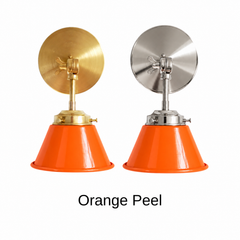 An orange wall sconce with a glossy cone shade, shown in Orange Peel with brass or nickel hardware. It has a single light, a round backplate, and a swivel knuckle with a wing nut so you can tilt the shade toward a bed, a desk, or a sink. Use it as a bedside sconce in a kids room, a vanity light in a bathroom, or a task light over a kitchen sink. Orange pairs well with pink or blue walls, white tile, and pale wood, so it suits playful, retro, and colorful modern decor.