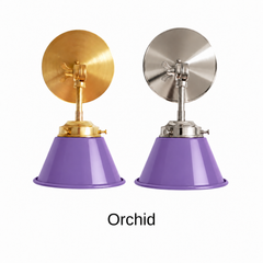 A purple wall sconce with a glossy cone shade, shown in Orchid with brass or nickel hardware. It has a single light, a round backplate, and a swivel knuckle with a wing nut so you can tilt the shade toward a bed, a mirror, or a sink. Hang one by a bed, a pair beside a bathroom mirror as a vanity light, or one in a teen room or reading nook. Orchid looks great with chartreuse or marigold accents, pink walls, and brass, so it suits maximalist, eclectic, and playful bedroom decor.