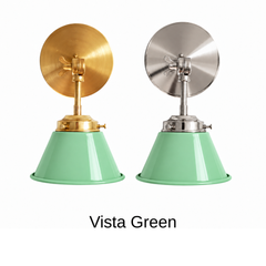 A mint green wall sconce with a glossy cone shade, shown in Vista Green with brass or nickel hardware. It has a single light, a round backplate, and a swivel knuckle with a wing nut so you can angle the shade toward a bed, a mirror, or a sink. Hang one by a bed, a pair beside a bathroom mirror as a vanity light, or one over a kitchen counter. Soft mint looks good with pink tile, white cabinets, and warm brass, so it suits 1950s vintage, jadeite kitchen, and pastel cottage rooms.