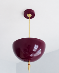 Black cherry pendant light with a brass spike finial, the Alexander Pendant sends light up instead of down, so the glossy burgundy dome bounces a warm glow off the ceiling. That uplight pendant design paired with the oversized art deco spike gives it a moody, jewel-toned weight most colorful lighting doesn't have. Dramatic dining room pendant, statement entryway light, or maximalist ceiling light for dark academia decor, moody traditional homes, and colorful rooms that want real presence overhead.