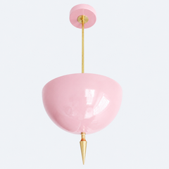 Blush pink pendant light with a brass spike finial, the Alexander Pendant sends light up instead of down, so the glossy pink dome bounces a soft, romantic glow off the ceiling. That uplight pendant design paired with the oversized art deco spike gives the sweetness a hard architectural edge instead of letting it go too soft. Statement girls room pendant, nursery ceiling light, or grandmillennial dining room fixture for maximalist decor that wants real presence overhead without losing its feminine charm.