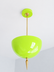 Handmade chartreuse pendant light in a glossy, electric yellow-green that steals the show — a high-gloss powder-coated dome in vivid lime-chartreuse, lifted by a slim brass stem and a hand-turned brass finial. The color is high-energy and saturated: it reads zesty neon-lime in daylight and glows acid-bright under lamplight, so it delivers a real jolt of personality against warm brass, white walls, natural wood, or a deep moody backdrop. Perfect over a kitchen island, a bar nook, a studio, or an entryway tha