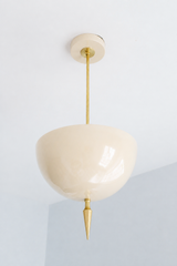 Handmade cream pendant light that proves a bold shape can still read as a neutral — a high-gloss powder-coated dome in soft warm ivory, lifted by a slim brass stem and a hand-turned brass finial. The upward-facing shade throws a soft, ambient uplight that washes the ceiling and warms the whole room, while the creamy tone blends effortlessly into any palette instead of competing with it. A sculptural fixture that quietly goes with everything — brass, wood, white walls, or color. Perfect over a kitchen island