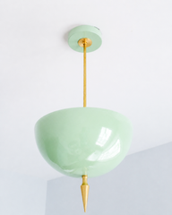 Mint green pendant light with a brass spike finial, the Alexander Pendant sends light up instead of down, so the glossy mint dome bounces a soft glow off the ceiling. That uplight pendant design paired with the oversized art deco spike gives it real presence without feeling heavy, a fresh, playful take on maximalist lighting. Statement dining room pendant, nursery ceiling light, or colorful entryway fixture for pastel traditional homes and anyone building a room with personality overhead.