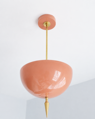 Peach pendant light with a brass spike finial, the Alexander Pendant sends light up instead of down, so the glossy peach dome bounces a soft, warm glow off the ceiling. That uplight pendant design paired with the oversized art deco spike gives it a feminine, maximalist edge, structured enough to anchor a room but soft enough to feel welcoming. Statement dining room pendant, nursery ceiling light, or colorful entryway fixture for grandmillennial homes and maximalist decor that wants warmth overhead.
