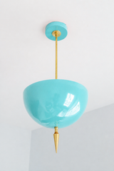 Poolside blue pendant light with a brass spike finial, the Alexander Pendant sends light up instead of down, so the glossy blue dome bounces a soft glow off the ceiling. That uplight pendant design paired with the oversized art deco spike gives it retro coastal charm with real architectural weight, like a vintage pool tile turned into a light fixture. Statement dining room pendant, sunroom ceiling light, or colorful entryway fixture for retro coastal homes and maximalist decor that wants personality overhea