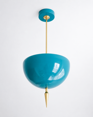 Handmade teal pendant light in a rich, glossy teal blue — a high-gloss powder-coated dome in true blue-green, lifted by a slim brass stem and a hand-turned brass finial. The color is vivid and saturated: it reads clear teal in daylight and deepens under lamplight, so it pops against brass, natural wood, or white walls while still working like a jewel-toned neutral. Perfect over a kitchen island, powder room, sunroom, or entryway that needs a confident hit of color. Shop handmade teal pendant lighting, gloss