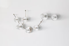 Angled view of the White Aquarius star sign vanity sconce in chrome with white powder coated steel disc details and globe bulbs, an astrology inspired bathroom wall light that feels sculptural, geometric, and playful for maximalist or modern interiors.