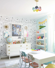 Kids craft room with pastel Arco Chandelier by Sazerac Stitches, colorful retro chairs, Star Wars poster, white dresser with brass hardware, and creative art storage shelves. Playful modern lighting for children’s spaces.