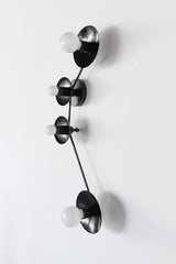 Aries zodiac constellation light fixture in all black metal with four round disc shades and white globe bulbs, modern sculptural wall sconce inspired by star signs, graphic mid century modern style lighting for hallway, entryway, bedroom, above nightstands, or moody bathroom vanity, minimalist black wall lighting for modern farmhouse, contemporary, maximalist, and eclectic interior design