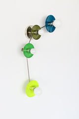 Aries four light wall sconce in color block Lagoon teal, olive, spring green and chartreuse, glossy disc shades with white globe bulbs, modern chrome arms, sculptural mid century modern wall lighting for a playful powder room, eclectic hallway, modern nursery, maximalist apartment, designer statement lighting on a white background.