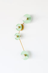 Aries zodiac wall sconce in Mint with warm brass hardware, constellation inspired modern wall light with four glossy powder coated steel disc shades and opal globe bulbs, sculptural statement sconce for a bathroom vanity over a mirror, powder room, entryway, bedside lighting, or colorful maximalist home decor, mid century modern brass and blue wall lighting that adds a bright saturated pop of color with a chic celestial vibe.