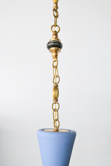 Partial view of the brass beaded chain dropping into the top of a pastel blue pendant shade, showing the sculptural silhouette and warm brass finish, a one of one statement pendant light for mid century modern interiors, coastal eclectic spaces, maximalist decor, kitchen island pendant lighting, entryway pendant light, and kids room ceiling lighting