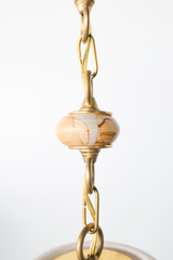 Close up of natural variation in teakwood spacer in a One of a kind cream pendant light with a sculptural hourglass shade hanging from a brass beaded chain, featuring terracotta round beads and light teakwood accent beads, a modern mid century inspired statement pendant for maximalist design lovers, perfect over a kitchen island, breakfast nook, entryway, nursery, or kids room lighting.