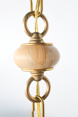 Close up of teakwood in One of a kind cream pendant light with a sculptural hourglass shade hanging from a brass beaded chain, featuring terracotta round beads and light teakwood accent beads, a modern mid century inspired statement pendant for maximalist design lovers, perfect over a kitchen island, breakfast nook, entryway, nursery, or kids room lighting.