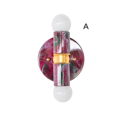A two-light wall sconce with a hand-marbled finish in black cherry, lilac, and green, centered on a matching round backplate. Brass hardware joins the upper and lower arms, each holding an exposed globe bulb. A bold choice for a bathroom, hallway, or anywhere that needs one strong colorful moment instead of a safe neutral fixture.