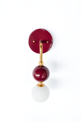 A detailed look at the black cherry and brass Ida sconce, showing the saturated glass orb and brass ball accents against the matching round backplate. Useful for checking finish and proportions before choosing it for a bathroom or hallway.