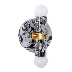 Detail shot of a handmade Thalia wall light featuring a bold black-and-white marbled finish, like abstract ink wash on glossy enamel. The brass collar and hardware create a refined contrast against the high-drama pattern, topped with a white globe bulb for soft, flattering light. A strong fit for moody powder rooms, black-and-white tile bathrooms, minimalist spaces that need edge, and contemporary interiors that mix clean lines with playful pattern.