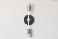 Black, white, and gray colorblocked Thalia sconce with brass accents, modern minimalist bathroom vanity wall light, sleek two-light fixture for contemporary interiors