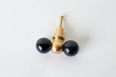 A head-on, symmetrical view of the black and brass double-ball knob, showing the finish and proportions clearly before installing it. Useful for checking scale and color against dark or graphic cabinetry.