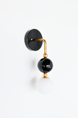 Another full view of the black and brass Ida sconce, showing the gooseneck arm, black glass orb, and frosted globe bulb from straight on. A sculptural option for anyone wanting a single-arm sconce with more shape than a standard fixture.