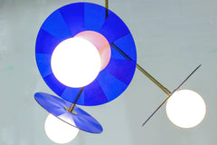 Wide shot: Mid-century modern pendant light fixture with bright blue discs bathes the room in a soft glow.