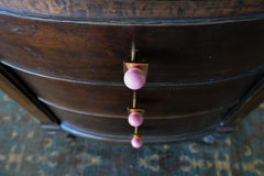 Close-up of blush pink and brass square gumball knobs installed on a vintage dark wood dresser. The modern drawer pulls feature glossy pink spheres and square brass bases, blending contemporary design with antique furniture for a bold, stylish contrast.