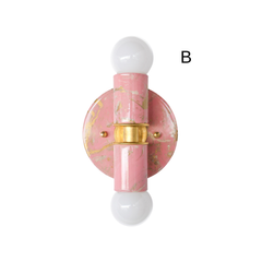 This blush pink marbled Thalia sconce combines creamy undertones, gold veining, and warm brass accents for a charming, collected look that feels both playful and elevated. Photographed on a light neutral background, the fixture’s compact scale and symmetrical shape make it easy to picture in a bathroom, hallway, vanity area, or colorful bedroom. Its hand-marbled finish means no two are exactly alike, giving each piece a unique, artful quality. A great fit for eclectic decor, maximalist interiors, pastel spa