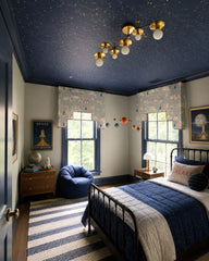 Space-inspired kids bedroom with a deep navy constellation ceiling, bold trim, and a cozy layered look with striped rug, vintage-style dresser, and rocket artwork. A brass flush mount ceiling light ties in warm metallic accents for a playful, elevated “space room” vibe. Great for boys bedroom ideas, galaxy bedroom, celestial wallpaper ceiling, navy and gold decor, and modern kids lighting.