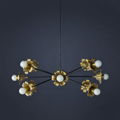 Octavia Blume chandelier by Sazerac Stitches, a sculptural brass and black chandelier photographed on a rich dark navy background. Floral-inspired brass “blume” cups with white globe bulbs radiate from slim black arms in a modern sputnik silhouette, mixing vintage botanical elegance with mid century modern lighting style. Statement ceiling light for dining rooms, entryways, bedrooms, and dramatic moody interiors, featuring warm brass tones, high-contrast black hardware, and an artful, gallery-like profile.