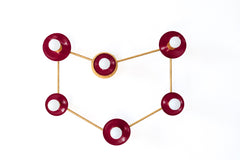 A Capricorn constellation wall sconce with six globe bulbs set in glossy burgundy disc shades, each one a star, linked by thin raw brass rods that trace the sea goat sign. The deep red is a nod to garnet, the January birthstone. Hang it over a bed, a sofa, or a home bar cart. Burgundy and brass suit moody celestial decor, jewel tone bedrooms, and zodiac wall art ideas, and it makes a standout birthday or holiday gift for the Capricorn in your life.