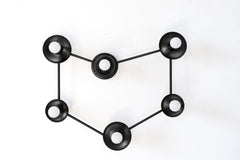 Six-light black wall sconce shaped like a capricorn constellation, with round matte black cups and white globe bulbs linked by thin black rods. Against a white wall the black reads like a line drawing of a star chart, with the bulbs as the stars. Mount it on a wall over a bed or sofa, or on the ceiling as a flush mount light. Black and white suits modern and minimalist rooms, a celestial or zodiac themed bedroom, and Scandinavian or industrial spaces with other black metal accents.