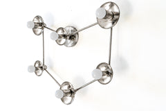 Nickel constellation light fixture with six white globe bulbs, each set out from a round silver cup and linked by thin nickel rods in an open star chart shape. From the side you can see how far the cups stand off the wall and the round wall plate in the middle. Hang it as a large wall sconce over a bed or sofa, or as a flush mount ceiling light. Bright silver suits modern and space age rooms, celestial bedroom lighting, and spaces with chrome or steel accents.