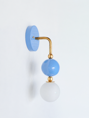A close look at a sky blue wall sconce built for colorful bathroom vanity lighting, powder room sconces, or nursery lighting ideas. Brass hardware and a glossy blue glass orb make this a strong pick for coastal traditional, Southern interiors, or grandmillennial bathroom decor. American made, RAL color lighting fixture, available for interior designer resource lighting projects.