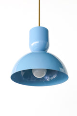 Soft blue is the color that makes a kitchen feel calm, sunny, and a little coastal, and this Taeuber pendant brings it in a clean, sculptural shape. The two-part silhouette stacks a rounded cup over a wide domed bell, all finished in a glossy celestial blue with a warm brass stem, shown here lit against white brick. It reads breezy and cheerful, the kind of statement lighting that turns an island, breakfast nook, or sink into a soft focal point. Hang one for a gentle pop of color or a row for rhythm. A love