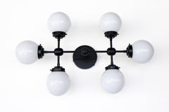 Large vanity light sconce or ceiling flushmount with 6 light bulbs.  Large, oversized wall sconce for a large bathroom or for a low 8 or 9 foot ceiling room that needs lots of light.  Modern shape with six white globes.  Great light fixture for a bathroom that does not have any natural light. Makes a small to medium bathroom bright enough to apply makeup.  Large vanity light in black, brass, or chrome.    Black and white large vanity light