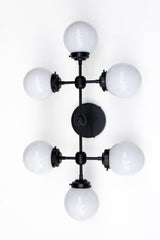 Large vanity light sconce or ceiling flushmount with 6 light bulbs.  Large, oversized wall sconce for a large bathroom or for a low 8 or 9 foot ceiling room that needs lots of light.  Modern shape with six white globes.  Great light fixture for a bathroom that does not have any natural light. Makes a small to medium bathroom bright enough to apply makeup.  Large vanity light in black, brass, or chrome.    Black and white large vanity light