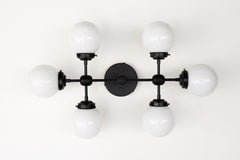 Large vanity light sconce or ceiling flushmount with 6 light bulbs.  Large, oversized wall sconce for a large bathroom or for a low 8 or 9 foot ceiling room that needs lots of light.  Modern shape with six white globes.  Great light fixture for a bathroom that does not have any natural light. Makes a small to medium bathroom bright enough to apply makeup.  Large vanity light in black, brass, or chrome.    Black and white large vanity light